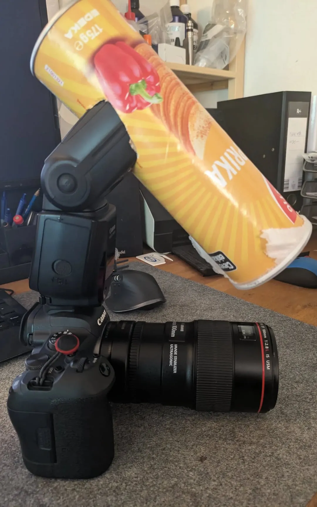 Canon-Kamera mit EF 100 mm Makroobjektiv und Aufsteckblitz. Eine leere Chipsdose steckt auf dem Blitzkopf und reicht schräg nach vorn über das Objektiv.